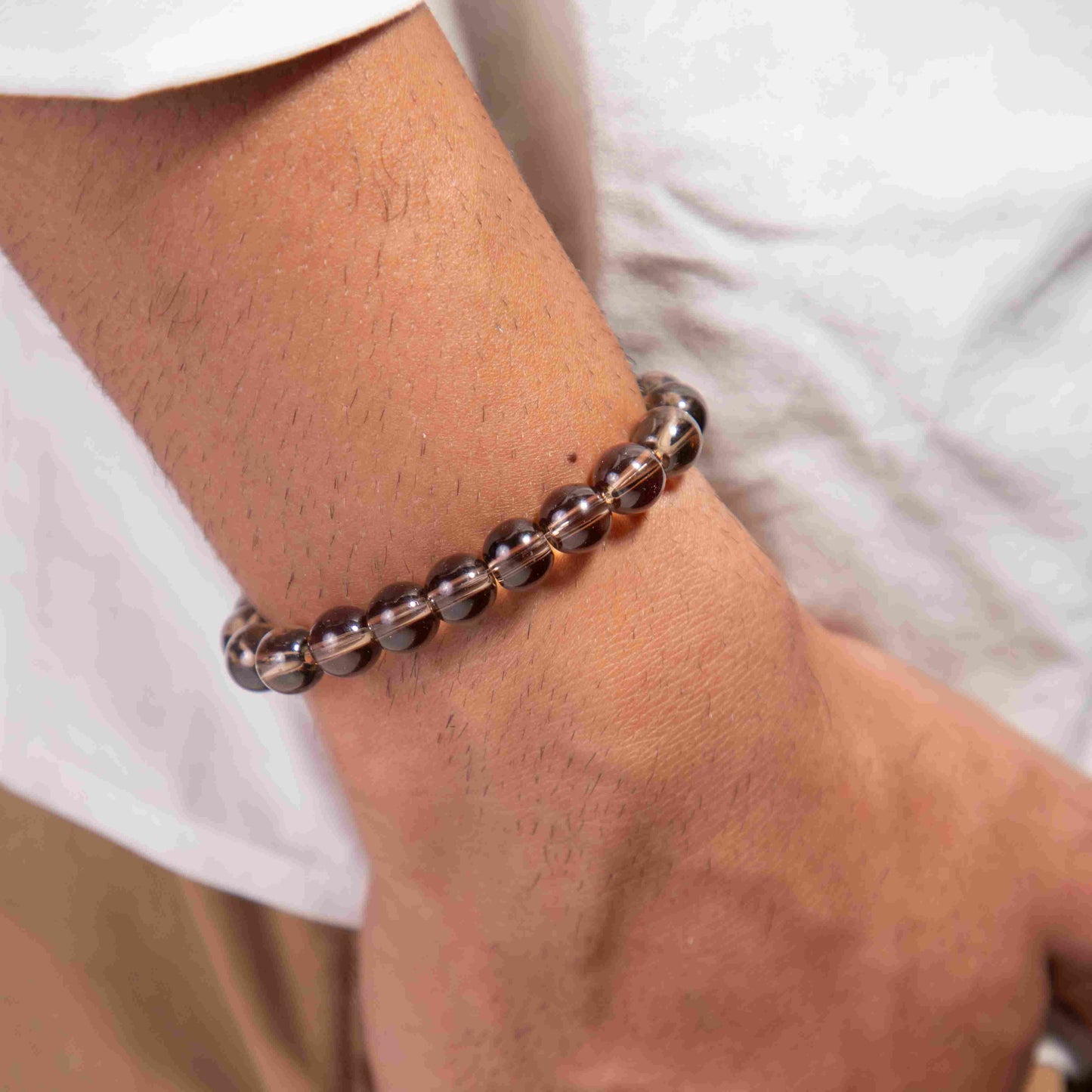 Close-up of a person's wrist wearing a metallic bracelet on a plain background